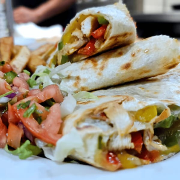 Chicken quesadillas with bell peppers, onions, and cheese, served with a side of fresh salsa.